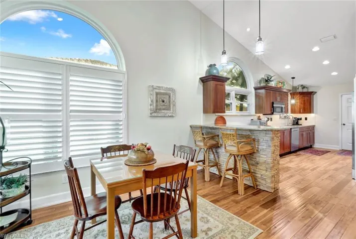 Dining area with light hardwood / wood-style floors and high vaulted ceiling