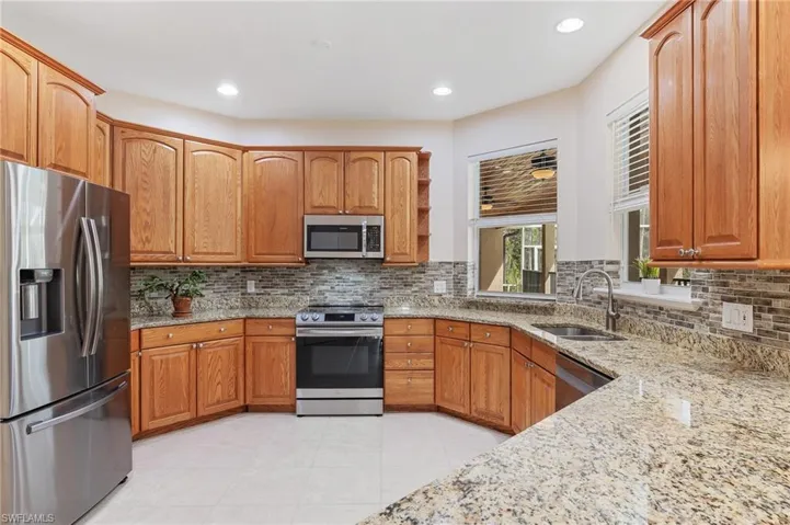 Wide open kitchen with oak cabinets, newer SS appliances, granite counter-tops. Pass-through window to lanai.