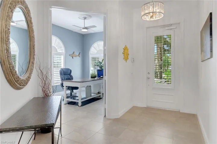 Foyer with light tile patterned flooring, a ceiling fan, and a chandelier