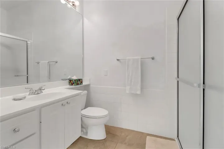 Full bathroom with tile walls, vanity, a shower stall, tile patterned flooring, and a wainscoted wall