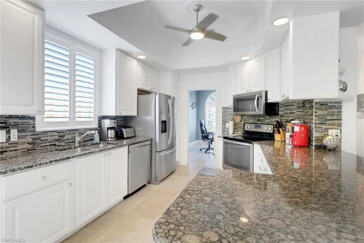 Kitchen with backsplash, appliances with stainless steel finishes, recessed lighting, and white cabinets