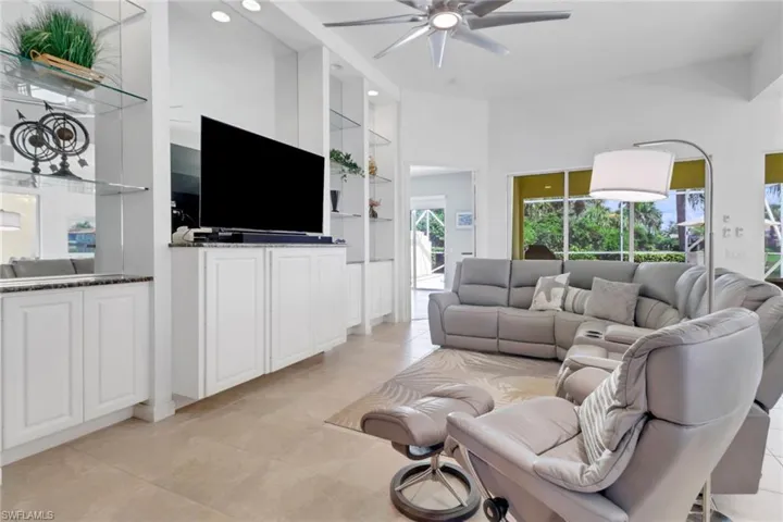 Living room featuring ceiling fan, built in shelves, light tile patterned floors, and recessed lighting