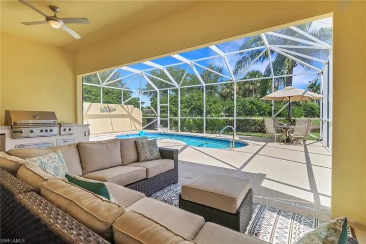 Outdoor pool featuring exterior kitchen, a patio area, a lanai, an outdoor hangout area, and ceiling fan