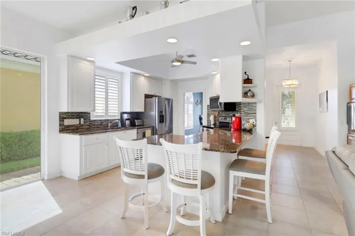 Kitchen with decorative backsplash, white cabinets, light tile patterned floors, a peninsula, and appliances with stainless steel finishes