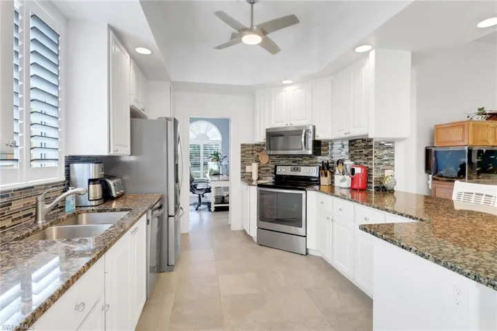 Kitchen with tasteful backsplash, appliances with stainless steel finishes, recessed lighting, a ceiling fan, and white cabinetry