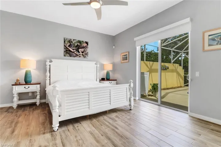 Bedroom featuring access to exterior, a sunroom, wood finished floors, and ceiling fan