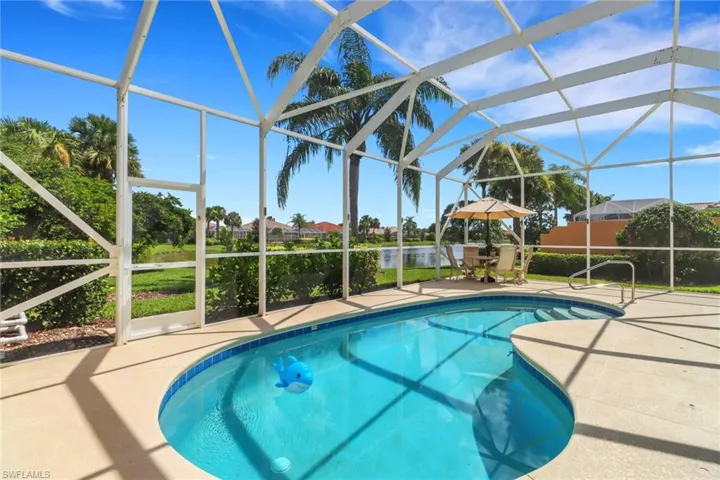 Outdoor pool featuring a patio area, a water view, and glass enclosure