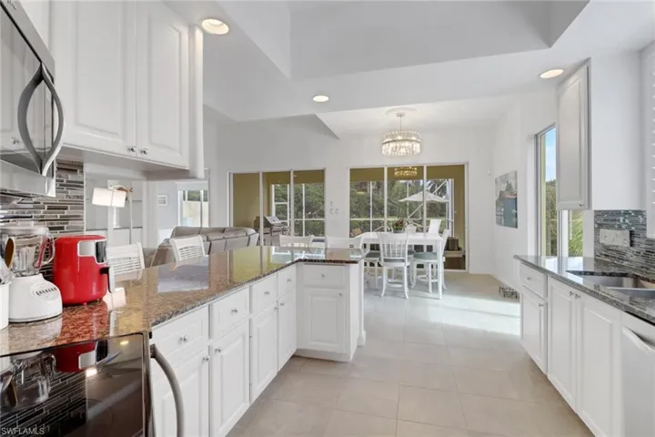Kitchen with backsplash, recessed lighting, stainless steel microwave, white cabinets, and a chandelier