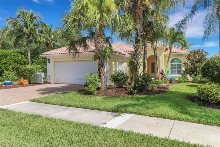 Mediterranean / Florida-style house featuring a garage, a front lawn, a tiled roof, and stucco siding