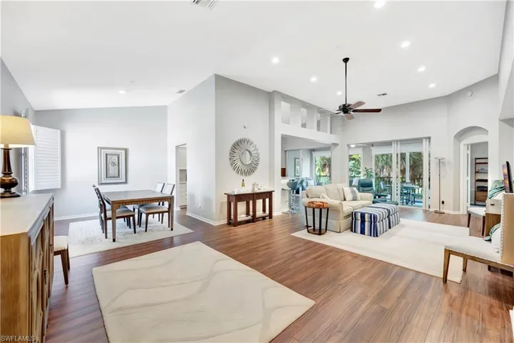 Living area with recessed lighting, a high ceiling, dark wood-style flooring, and a ceiling fan
