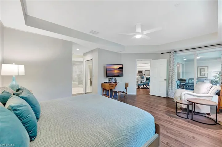 Bedroom featuring wood finished floors, visible vents, ensuite bathroom, and baseboards