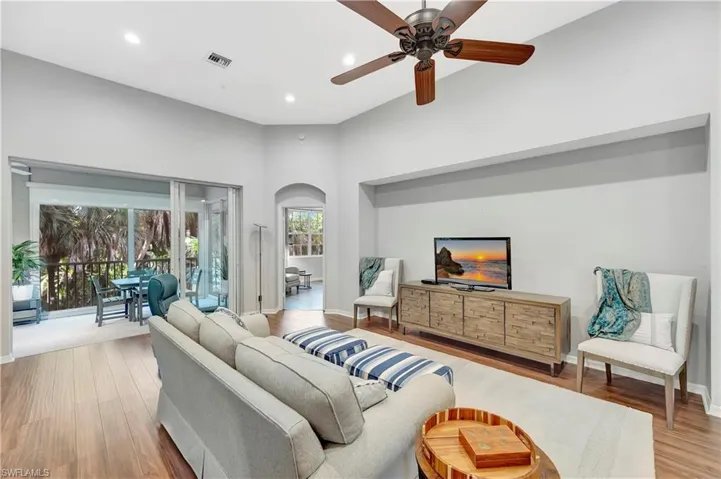 Living area with visible vents, a ceiling fan, wood finished floors, recessed lighting, and arched walkways