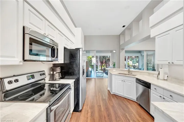 Kitchen with white cabinetry, light wood finished floors, appliances with stainless steel finishes, and a sink