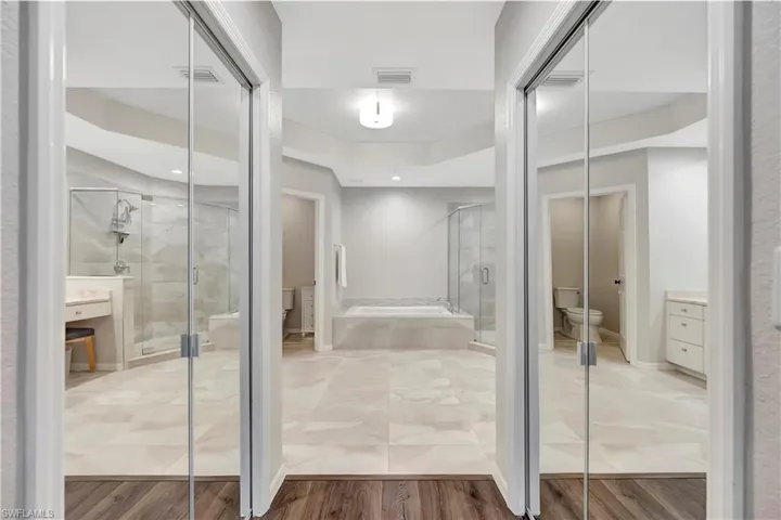 Full bath with toilet, wood finished floors, visible vents, and a stall shower