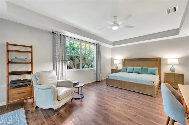 Bedroom featuring a ceiling fan, wood finished floors, visible vents, and baseboards