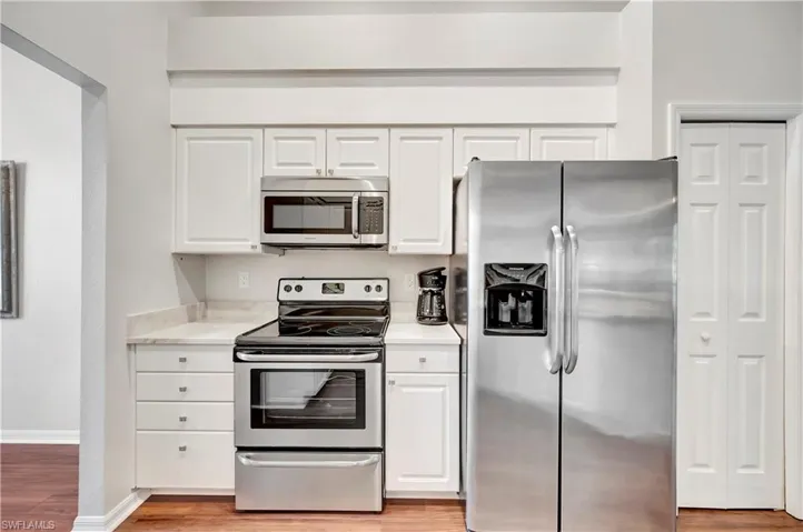 Kitchen featuring light wood finished floors, white cabinetry, appliances with stainless steel finishes, and light countertops