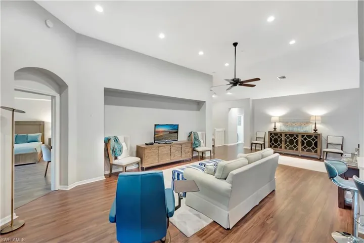 Living room featuring wood finished floors, recessed lighting, arched walkways, baseboards, and ceiling fan