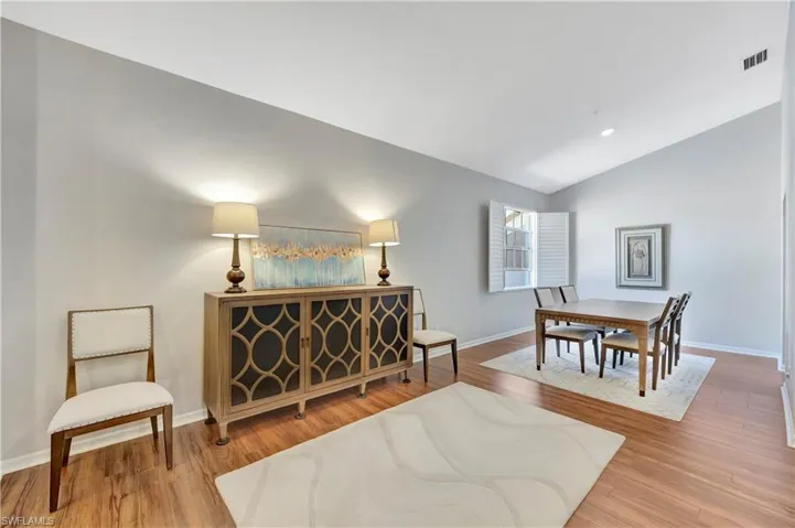 Sitting room featuring visible vents, baseboards, lofted ceiling, and wood finished floors