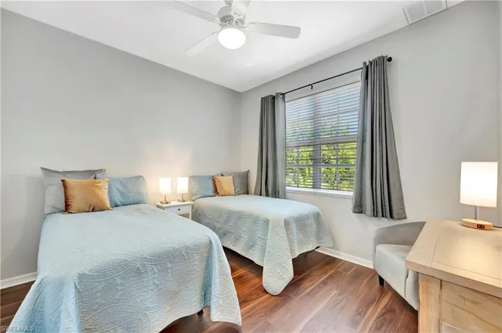 Bedroom with ceiling fan, visible vents, baseboards, and wood finished floors