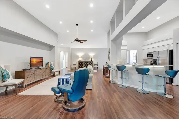 Living area featuring recessed lighting, a ceiling fan, a towering ceiling, and wood finished floors