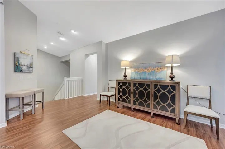 Sitting room featuring visible vents, an upstairs landing, baseboards, and wood finished floors