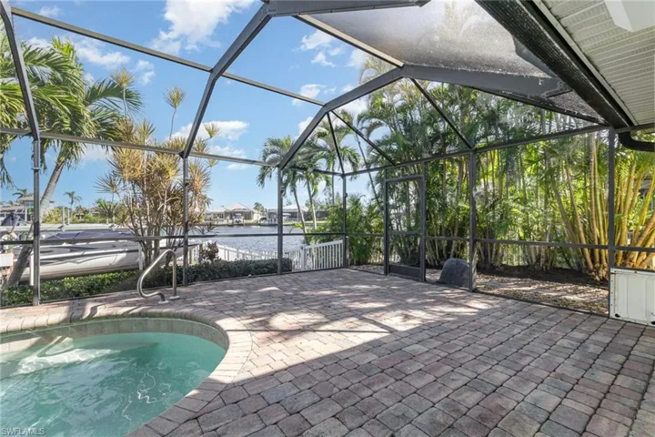 View of pool with glass enclosure, a patio area, and a water view
