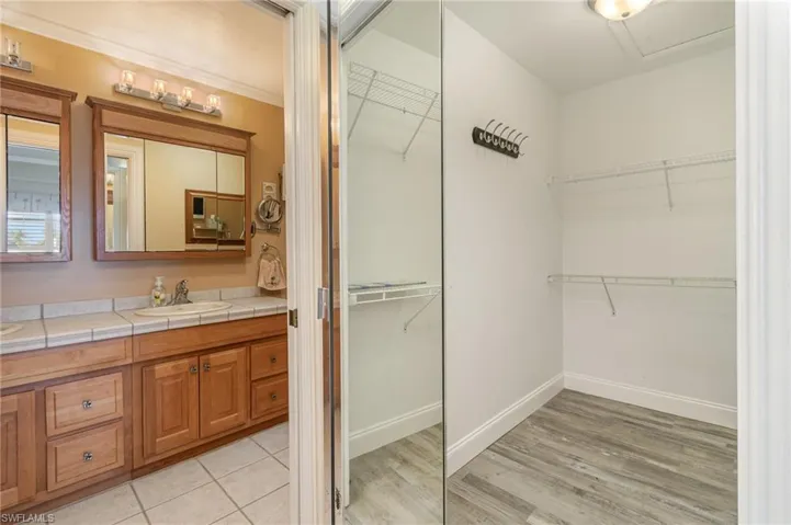 Master Bathroom with hardwood / wood-style floors and vanity and showing one of two walk in closets