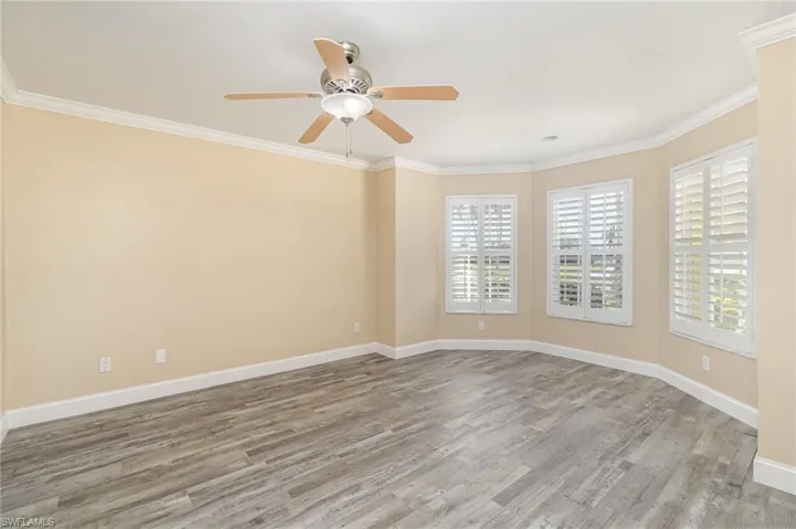 Bedroom 4 / den with hardwood / wood-style floors, ceiling fan, and crown molding and 1/2 bath