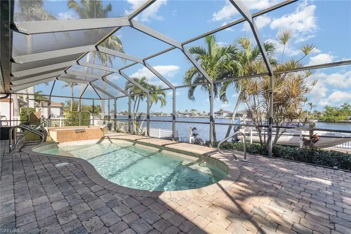 View of swimming pool with glass enclosure, a water view, and a patio