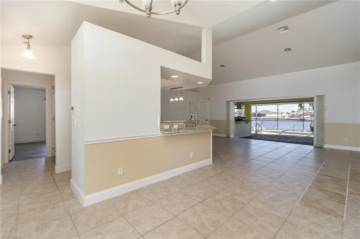 view from front door.  Living room featuring a water view, high vaulted ceiling, light tile patterned floors, and an inviting chandelier