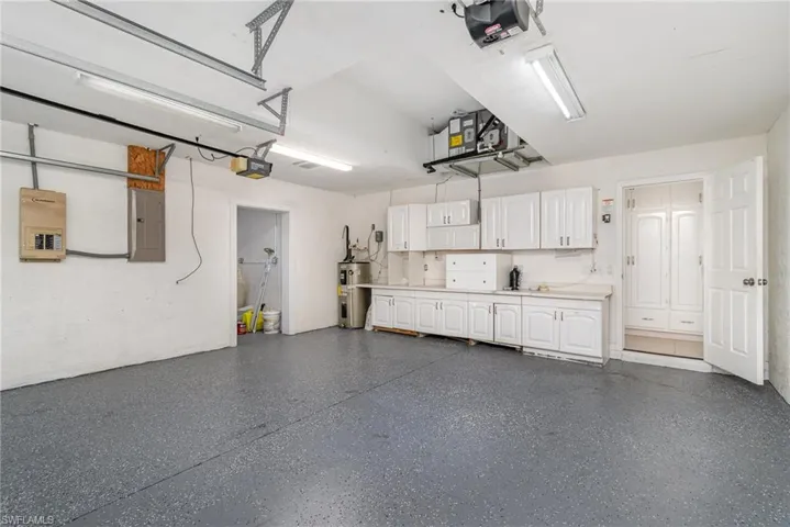 Two Car Garage with electric panel, water heater, and a garage door opener access to additional Golf cart garage