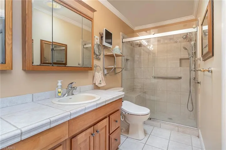 Master Bathroom featuring tile patterned flooring, vanity, an enclosed shower, and ornamental molding