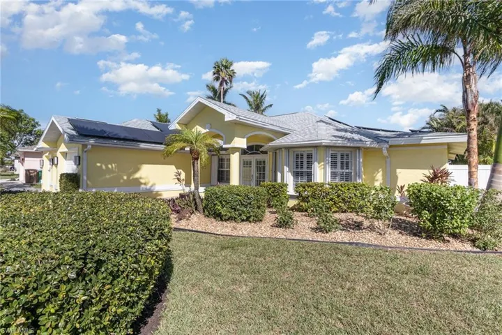 Single story home featuring solar panels and a front lawn