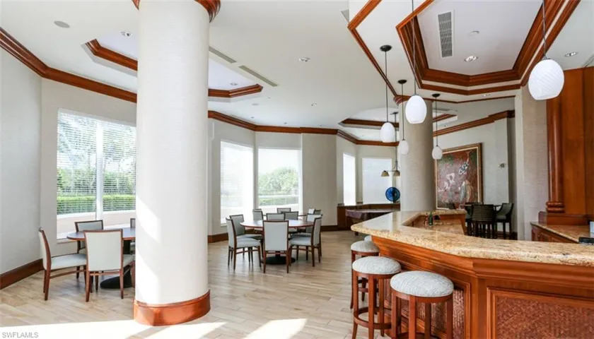 Kitchen with decorative columns, a raised ceiling, ornamental molding, and light wood-style floors