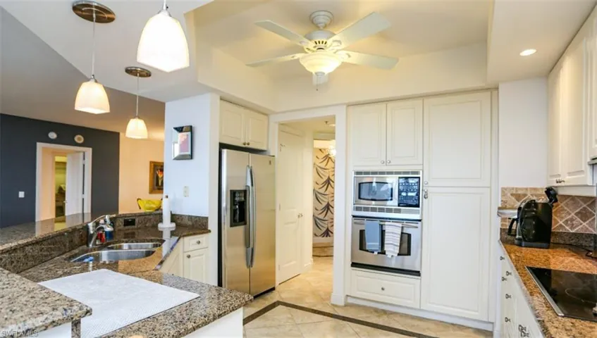 Kitchen featuring white cabinetry, decorative light fixtures, decorative backsplash, a sink, and appliances with stainless steel finishes
