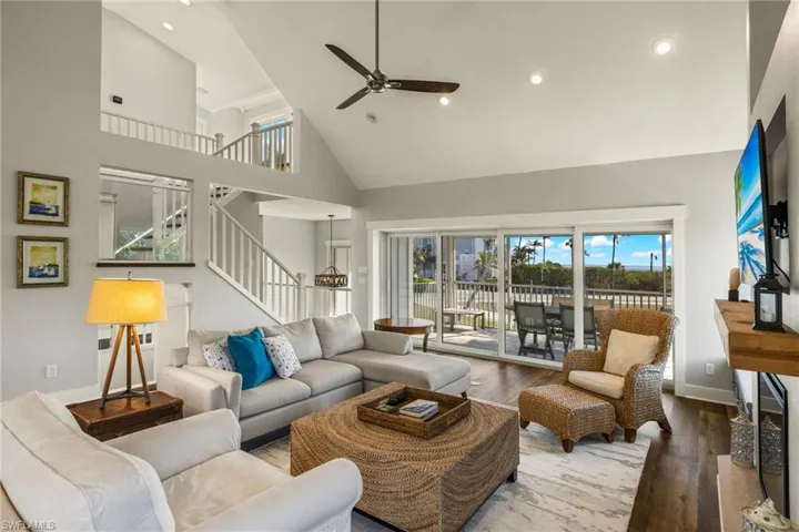 Living area with high vaulted ceiling, wood finished floors, recessed lighting, ceiling fan, and stairway