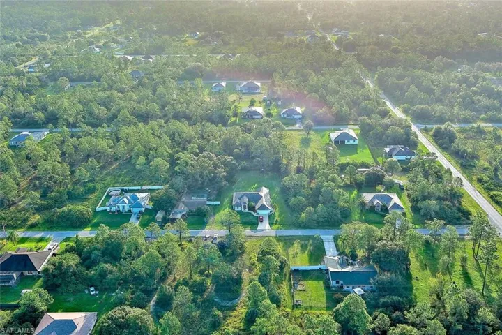 Aerial view of property's location with nearby suburban area and a forest