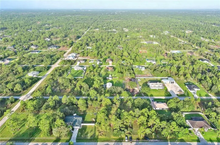Aerial view of property and surrounding area featuring a forest