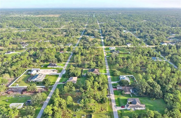 View of property location featuring nearby suburban area and a heavily wooded area