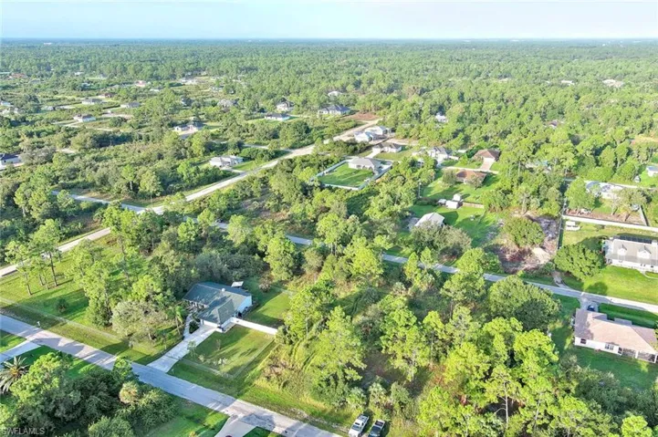 View of property location featuring a forest and nearby suburban area