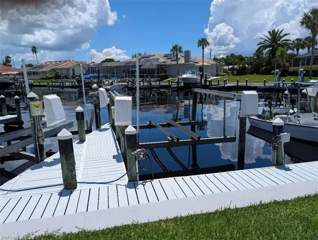 Dock area with boat lift, a water view, and a residential view