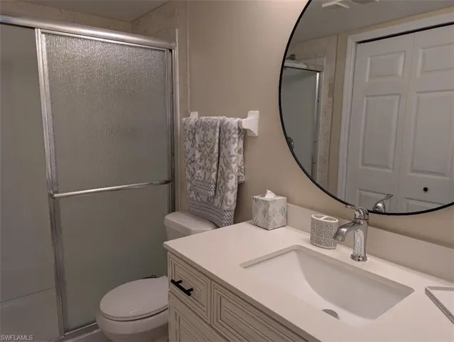 Bathroom with a stall shower, vanity, and a closet