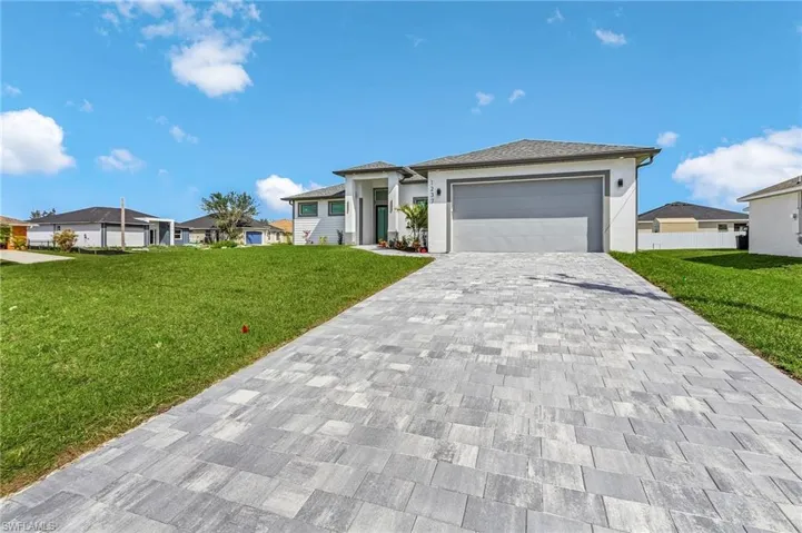 Prairie-style house with a front lawn, decorative driveway, a garage, and stucco siding