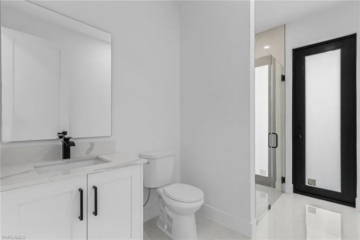 Bathroom with toilet, marble finish floor, a stall shower, baseboards, and vanity