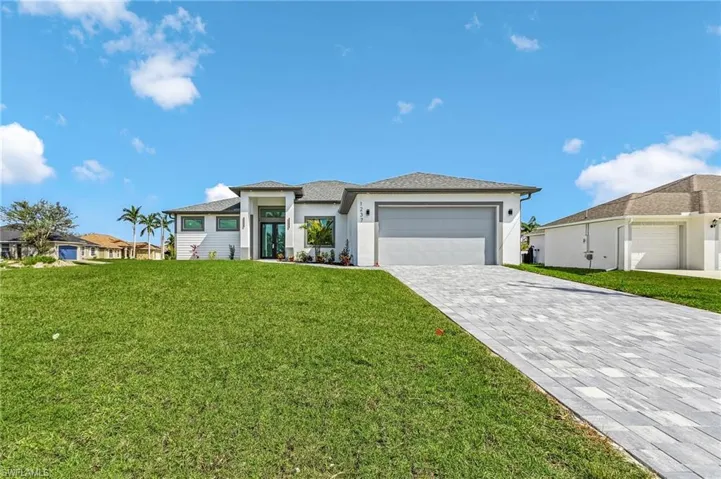Prairie-style house with a garage, decorative driveway, a front yard, and stucco siding