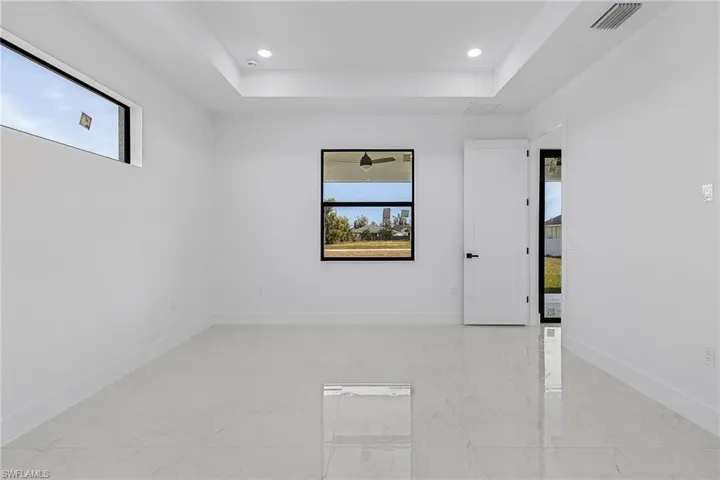 Unfurnished room featuring visible vents, recessed lighting, a raised ceiling, and baseboards