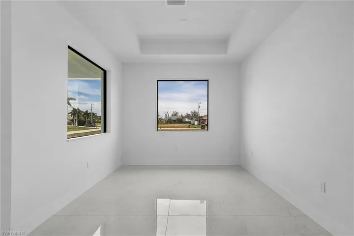 Unfurnished room featuring visible vents, marble finish floor, baseboards, and a tray ceiling