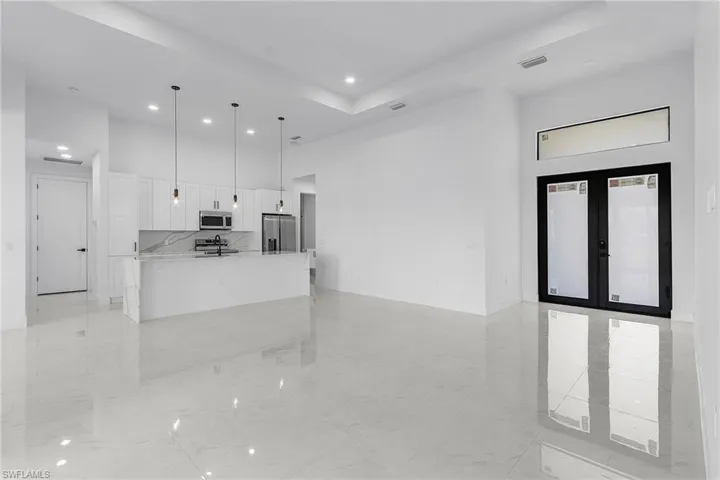 Kitchen featuring stainless steel appliances, white cabinetry, a towering ceiling, and french doors