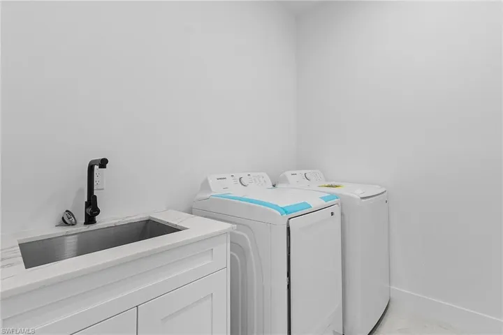 Laundry room with washing machine and clothes dryer, cabinet space, marble finish floor, and a sink