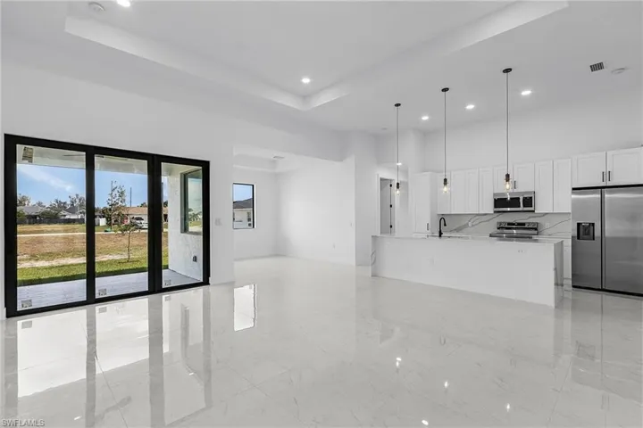 Kitchen with a high ceiling, white cabinets, marble finish floor, and appliances with stainless steel finishes